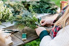 a woman is working on some plants at an outdoor table with scissors and other items