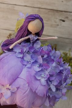 a doll sitting on top of a purple flower