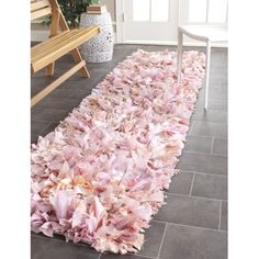 a large rug with pink flowers on it in front of a bench and door way