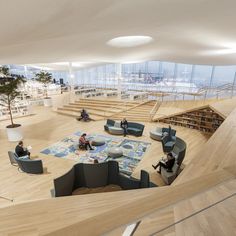 people are sitting on couches in an open area with stairs and bookshelves