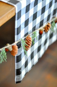 pine cones are hanging from a table with black and white checkered cloth on it