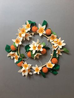 an orange and daffodil wreath with green leaves on a gray background,