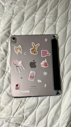 an apple laptop covered in stickers on a bed