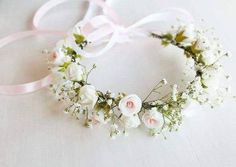 a white flower crown with pink and white flowers on it's headband, sitting on a table