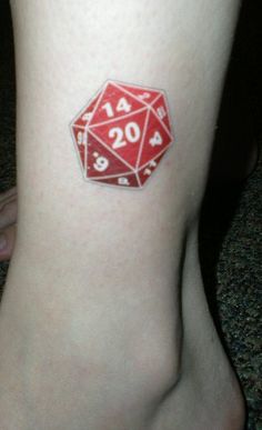 a red dice tattoo on the leg of a woman's foot, which reads 20