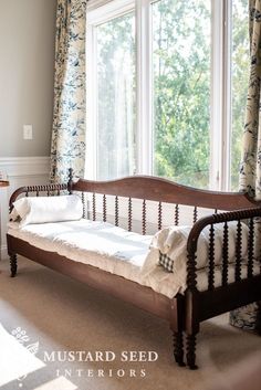 a wooden day bed sitting next to a window