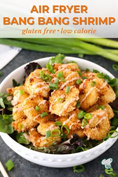 an air fryer bang bang shrimp in a white bowl with green onions on the side