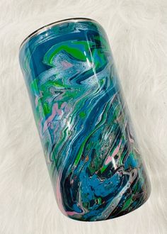 a blue and green vase sitting on top of a white fur covered floor