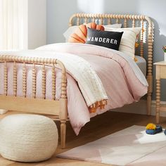 a bed with pink sheets and pillows in a room next to a white rug on the floor