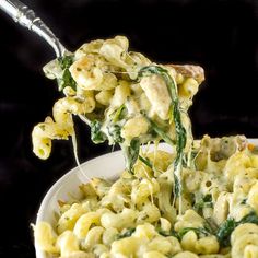 a spoon full of macaroni and cheese being lifted from a bowl