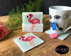 two coasters with flamingos on them and a coffee cup next to one that has a spoon in it