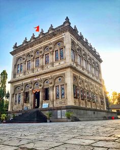 an old building with a red flag on the top and stairs leading up to it