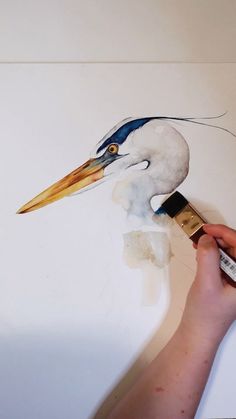 a bird is being drawn on a piece of paper with a brush in it's left hand