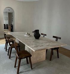 a table with chairs and a vase on it in the middle of an empty room