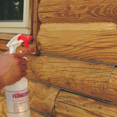 a person spray painting wood on the side of a house with red and white paint