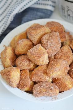 a white bowl filled with sugared donuts on top of a table