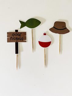 three wooden pins with hats on them and one has a sign that says gone fishing