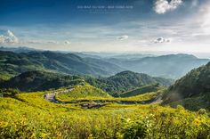 a scenic view of mountains and valleys from the top of a hill with a road winding through them