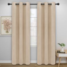 a beige curtain hanging in front of a window with white walls and wooden flooring