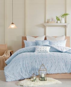 a bed with blue comforter and pillows in a room next to a table, chair and lamp