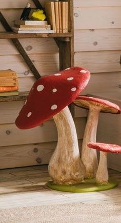 two red mushrooms sitting on top of a wooden floor