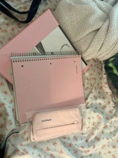 a pink notebook sitting on top of a bed