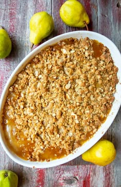 a dish filled with apple crisp on top of a wooden table next to lemons