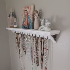 a shelf filled with lots of necklaces on top of a white wall next to a painting