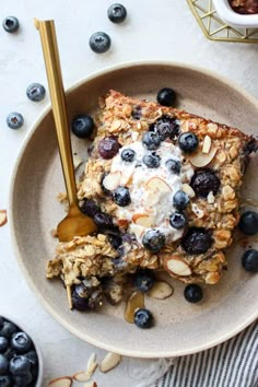 a bowl filled with granola, blueberries and yogurt on top of a table