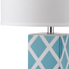 a blue and white table lamp with a white shade on the top, in front of a white background