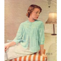 a woman sitting on top of a chair wearing a green sweater and white skirt with an orange striped pillow