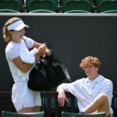 a man holding a tennis racquet on top of a tennis court next to a woman