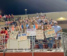 a group of people holding up signs in front of a crowd on bleachers