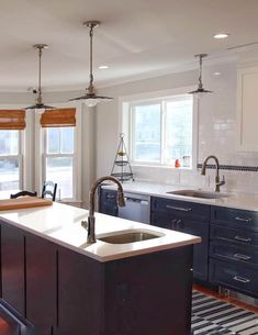 a kitchen with blue cabinets and white counter tops, an island in front of the sink