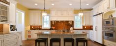 a large kitchen with white cabinets and marble counter tops, along with bar stools