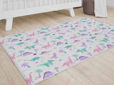 a child's rug with dinosaurs and palm trees on it in front of a white crib