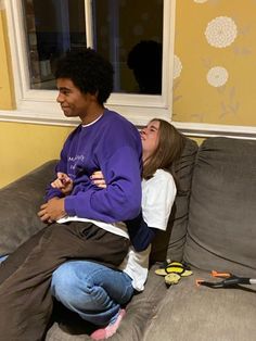 two people sitting on a couch with one holding the other