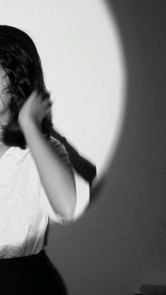 a woman is brushing her hair in front of a mirror with the light shining on her