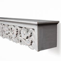 a white wooden shelf with an ornate design on it's top and bottom edge