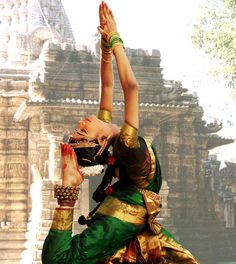 a woman is doing yoga in front of a temple