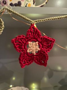 a crocheted star ornament hanging from a string with lights in the background