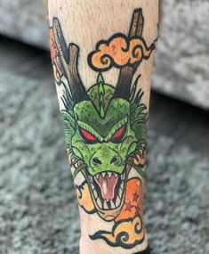 a tattoo on the leg of a person with a green dragon head and red eyes