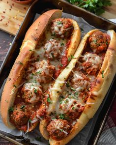 two hot dogs with meatballs and cheese on them