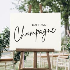 a sign that says but first champagne on it in front of some chairs and trees