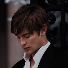 a man in a suit looking down at his cell phone while wearing a white shirt and black blazer