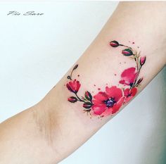 a woman's arm with red flowers on it and watercolor paint splatters