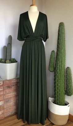 a green dress sitting on top of a wooden floor next to a cactus and cacti