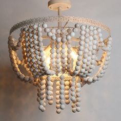 a white chandelier with beads hanging from it's center point and two lights on each side