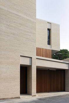 two garages on the side of a brick building with wooden doors and window frames