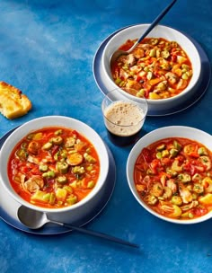 three bowls of soup on a blue table